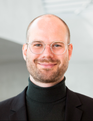 Professional headshot of Wolfgang Halter smiling, wearing glasses and a black turtleneck.