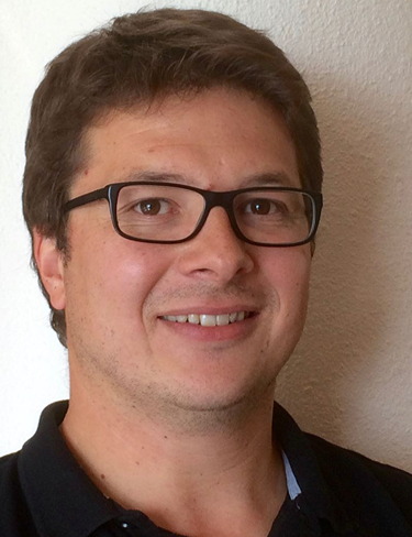 Guillaume Wantz smiling at the camera wearing black polo t-shirt and glasses