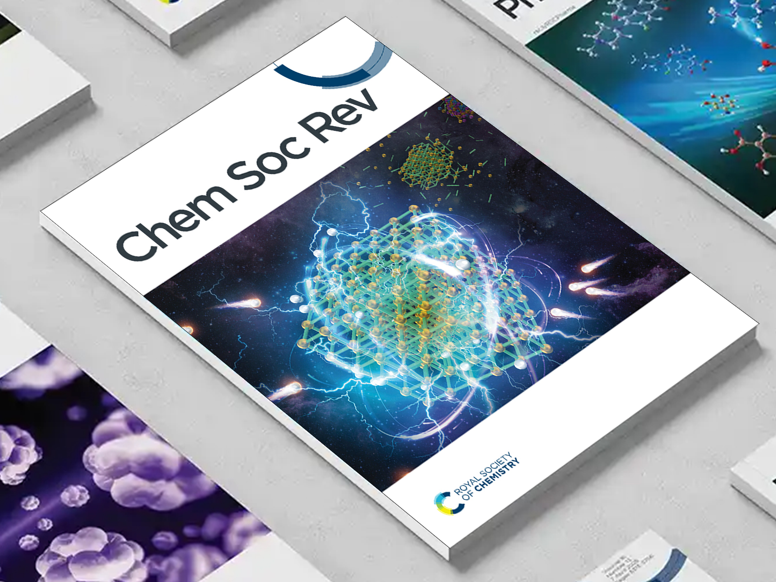 the Chem Soc Rev journal among a group of other journals on a desk