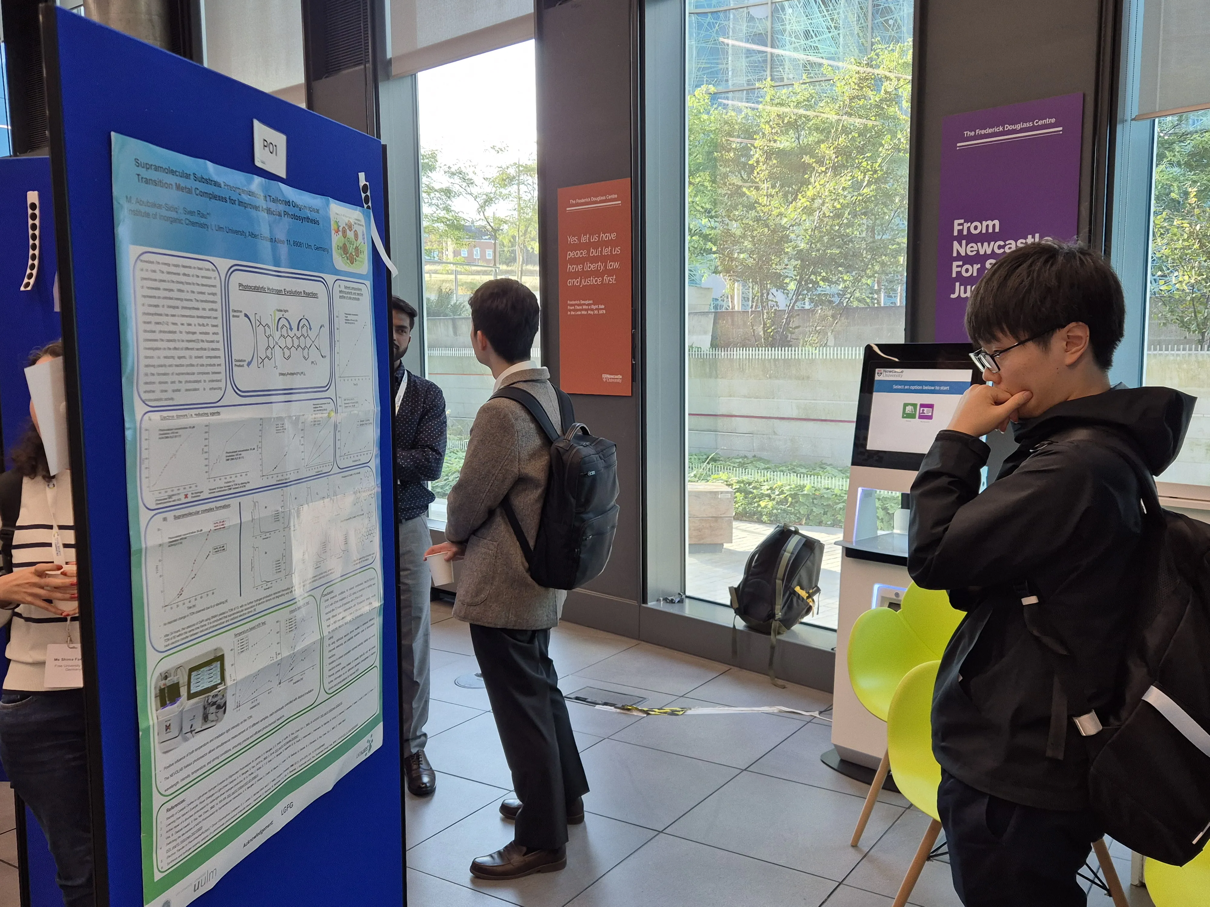 International Solar Fuels Conference - attendees check out the poster presentations A man standing on the right of the shot looks intently at a poster while other people chat in the background