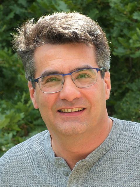 Vincent Artero outside, smiling to camera, wearing glasses and grey jumper