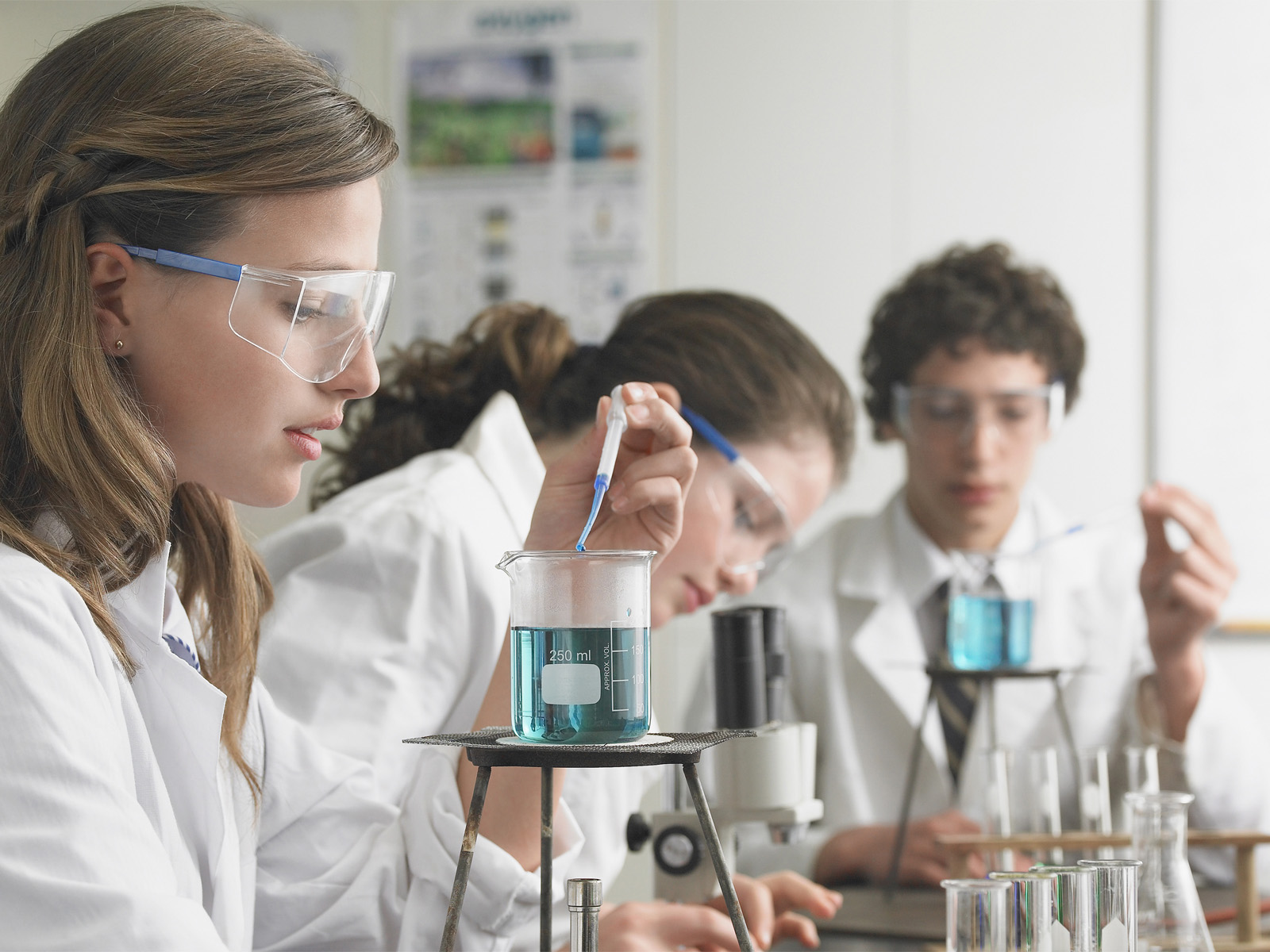Teenage students doing simple chemistry experiments in a teaching lab. 