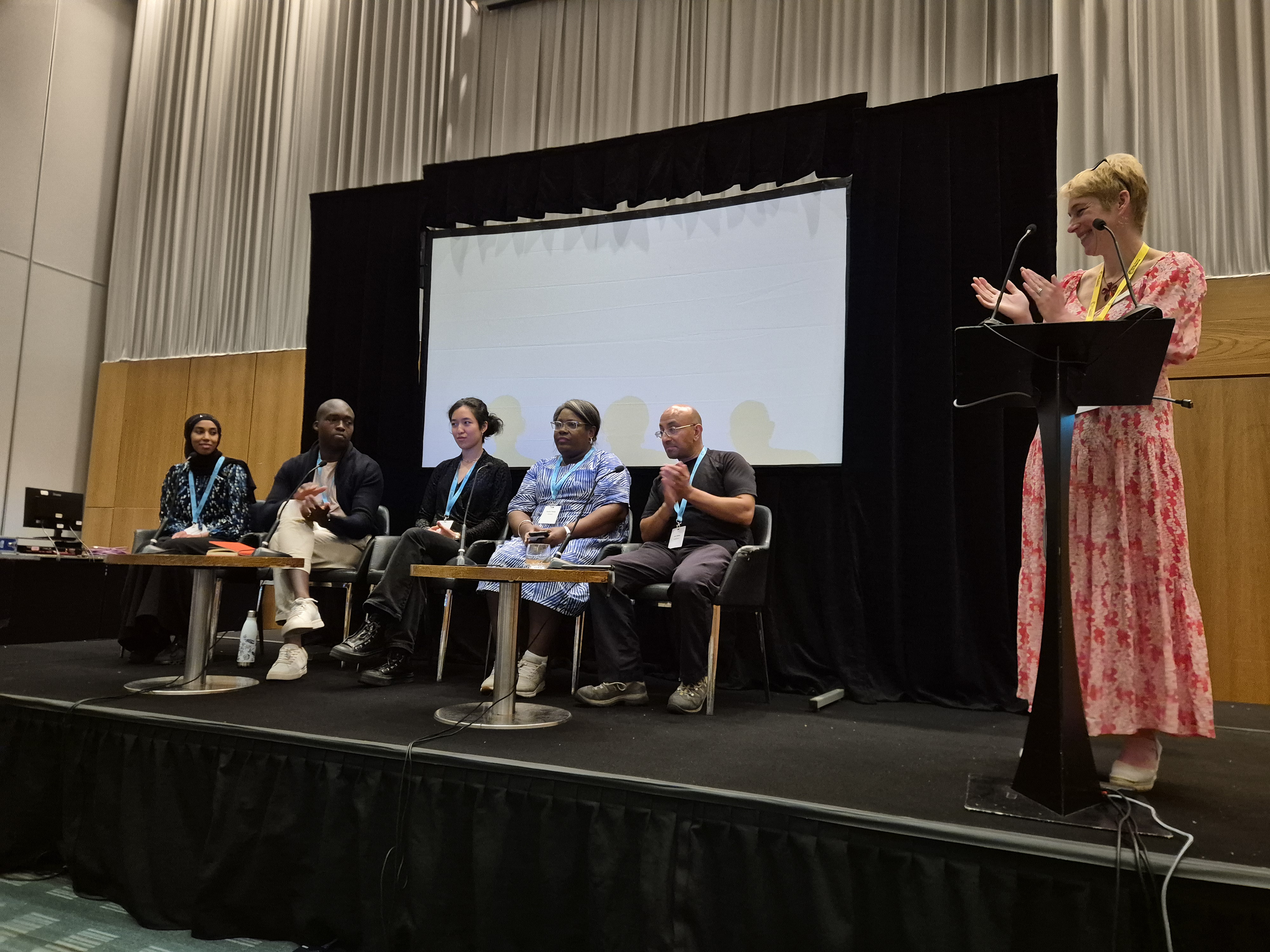 Dr Jo Reynolds (right) stands behind a lectern with five industry representatives