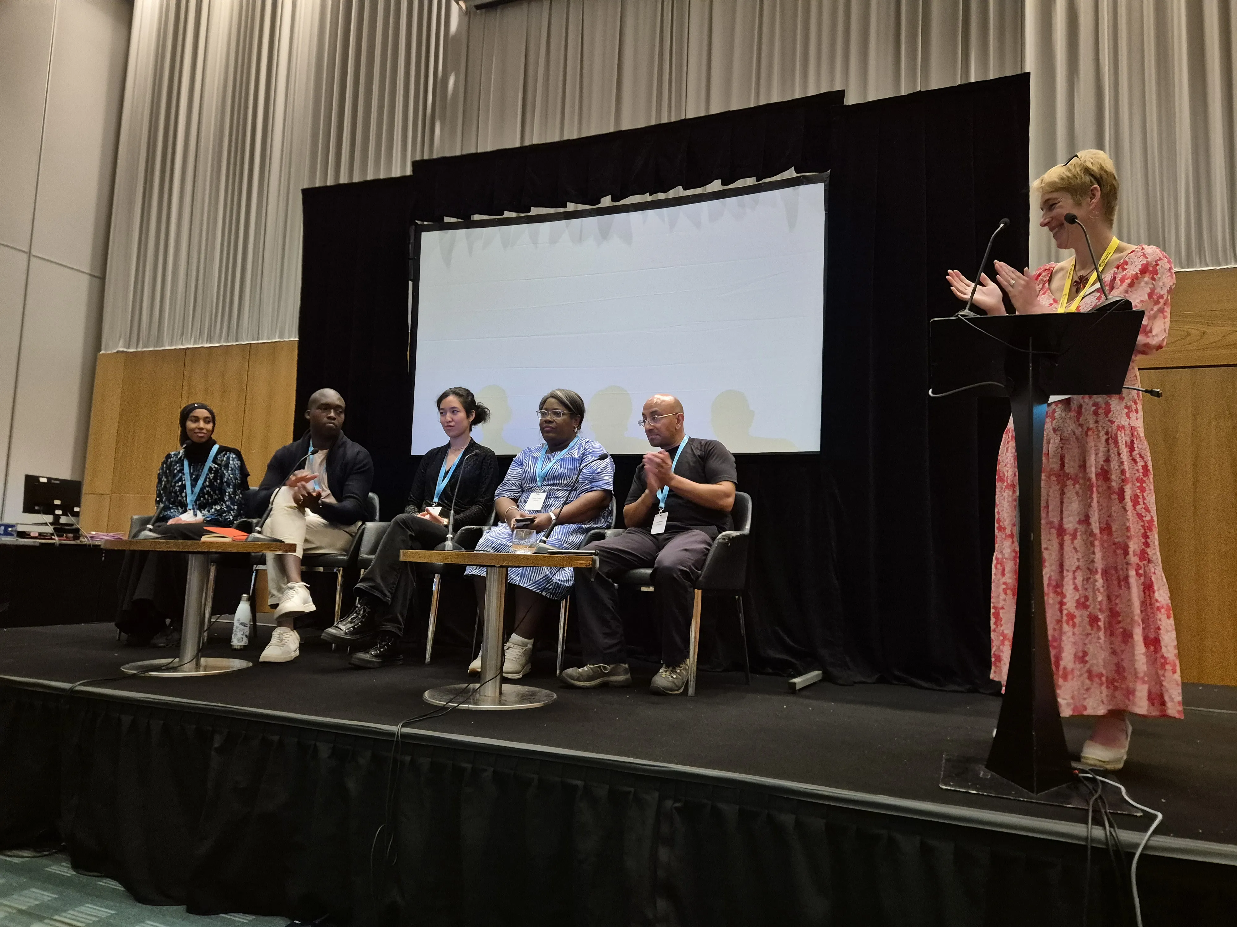 Broadening Horizons 5 - industry panel Dr Jo Reynolds (right) stands behind a lectern with five industry representatives