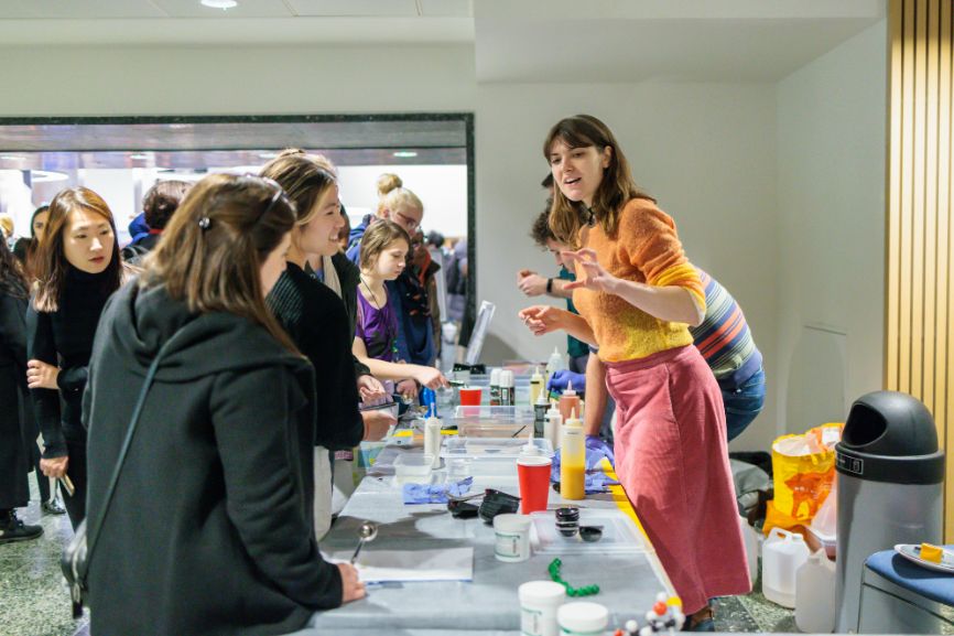 A woman on the right-hand side enthusiastically leads a demonstration to an interested group at a stall at the Imperial Lates event