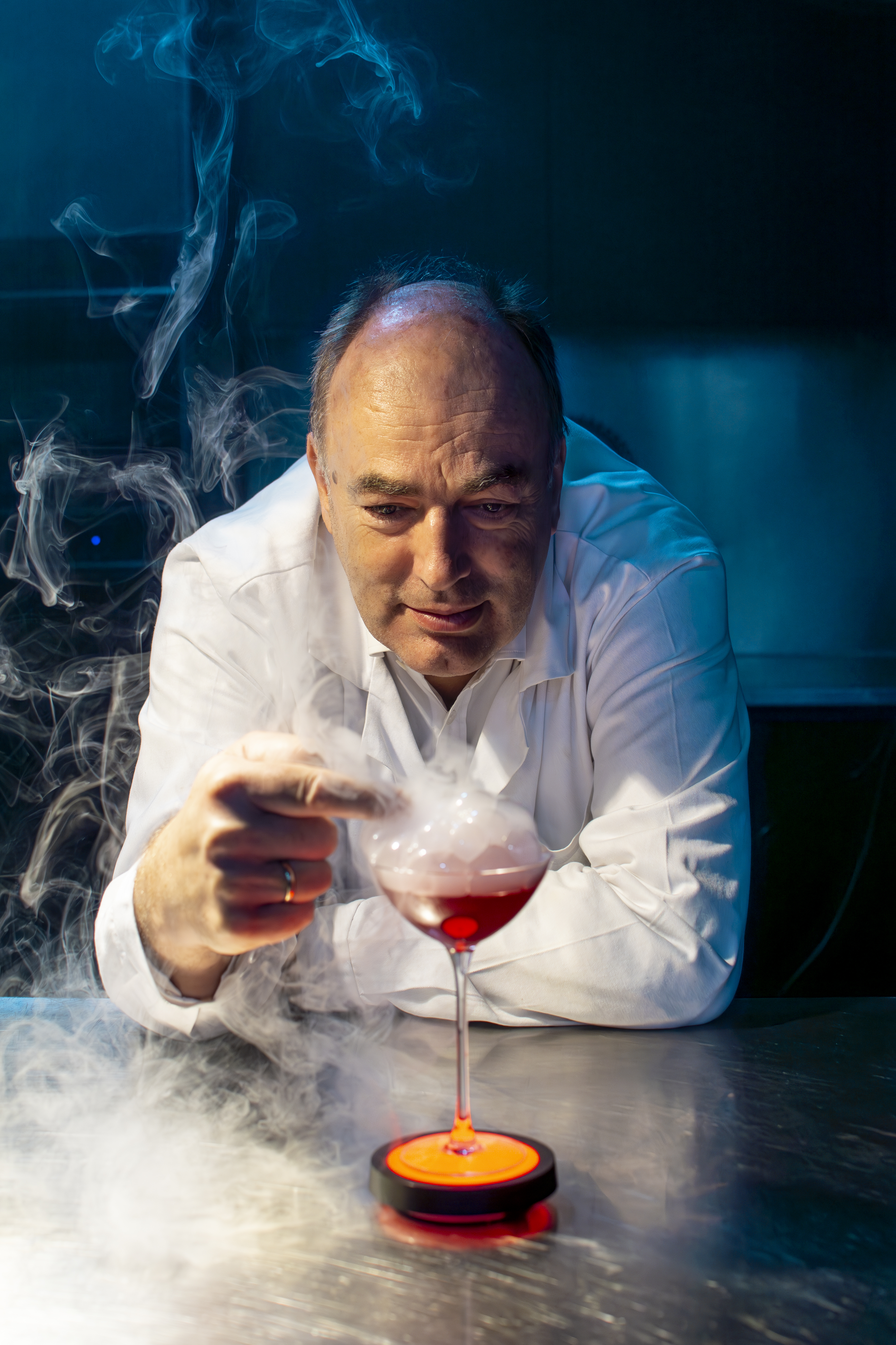 a man pointing at a glass of liquid