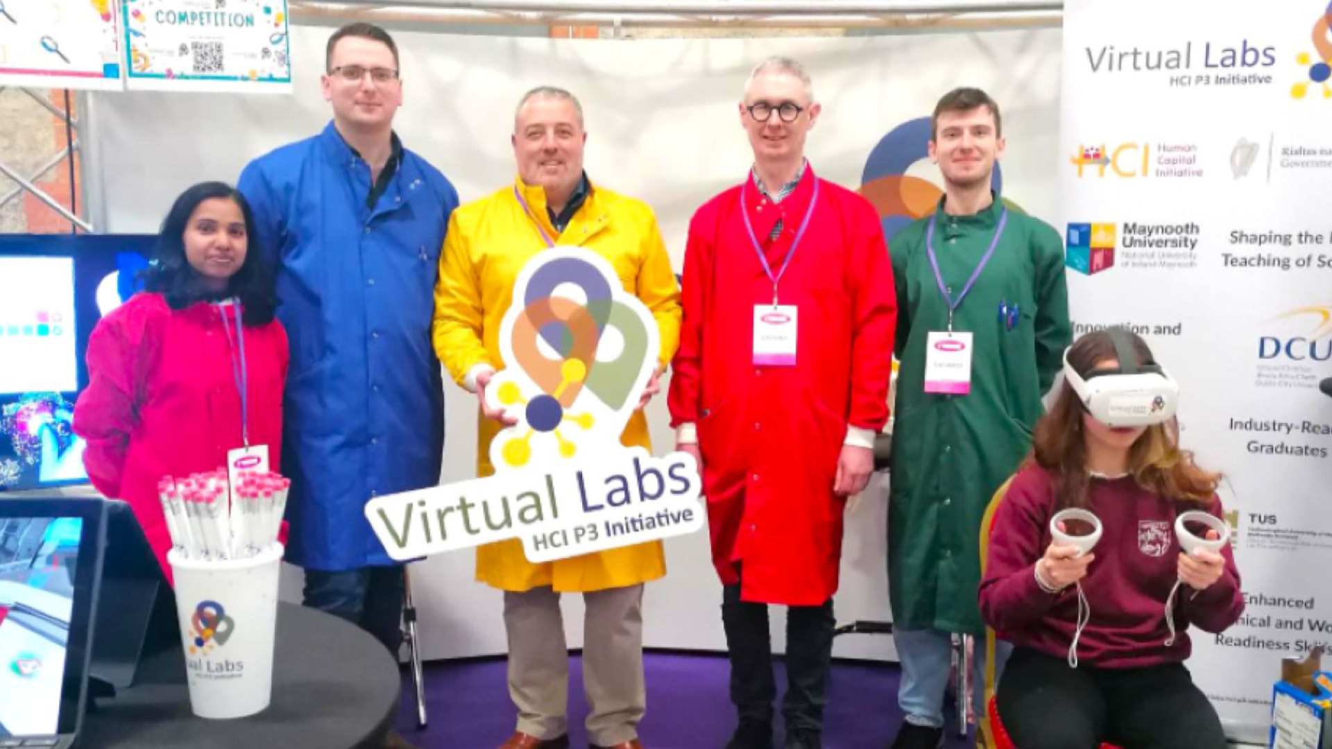 Virtual Labs Team in colourful lab coats with a student using virtual headset