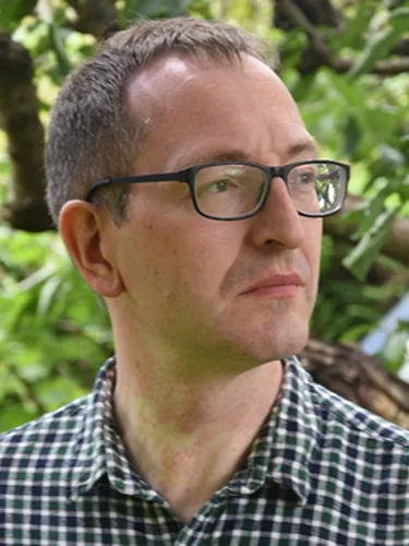 Aldo Guiducci Aldo Guiducci wearing checkered shirt and glasses while looking off-camera.