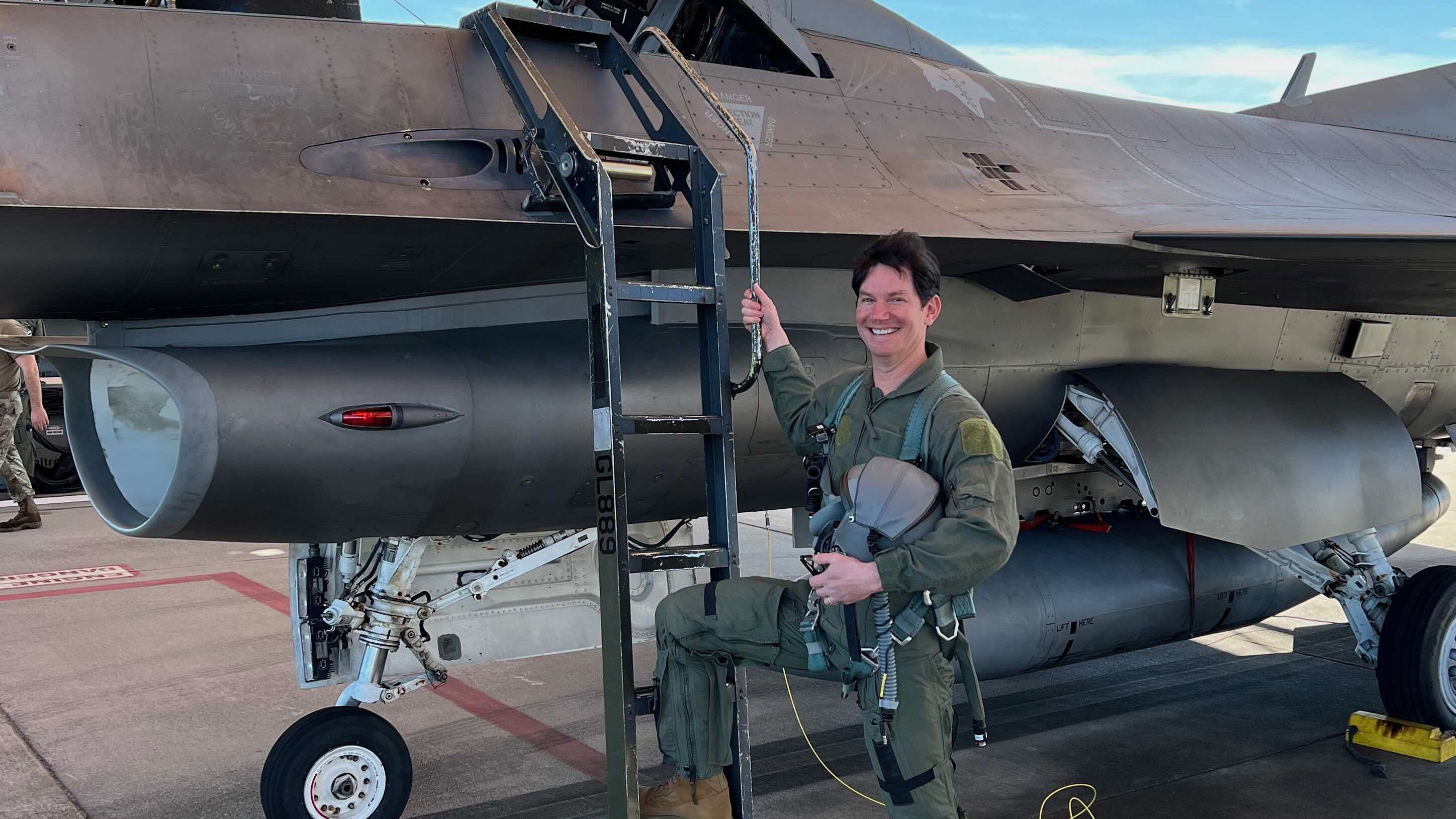 Professor Seth Cohen in uniform holding a ladder next to a small plane