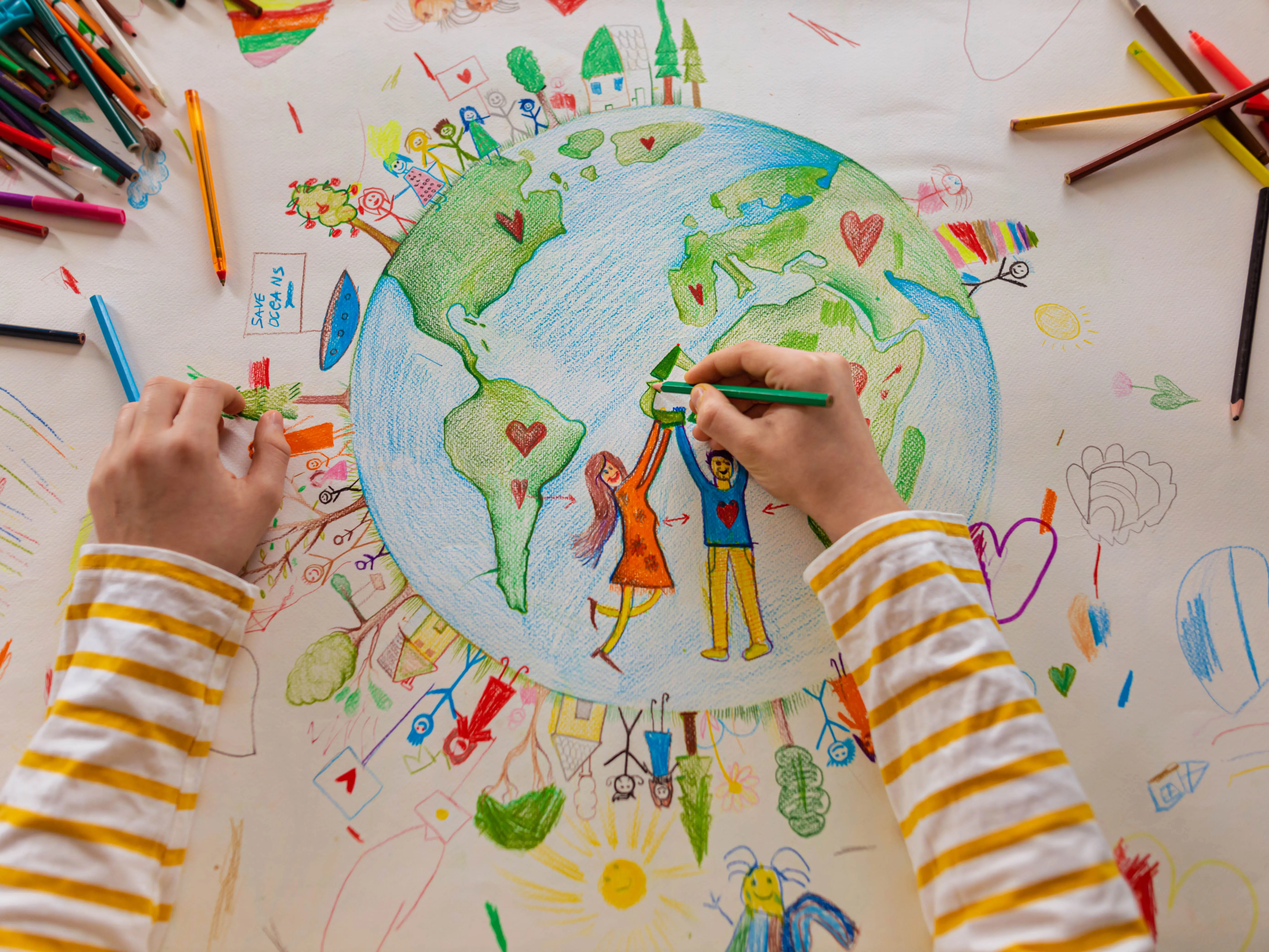 ccf-wellbeing-family-getty-1371150277 A child's hand drawing planet Earth with colourful pens