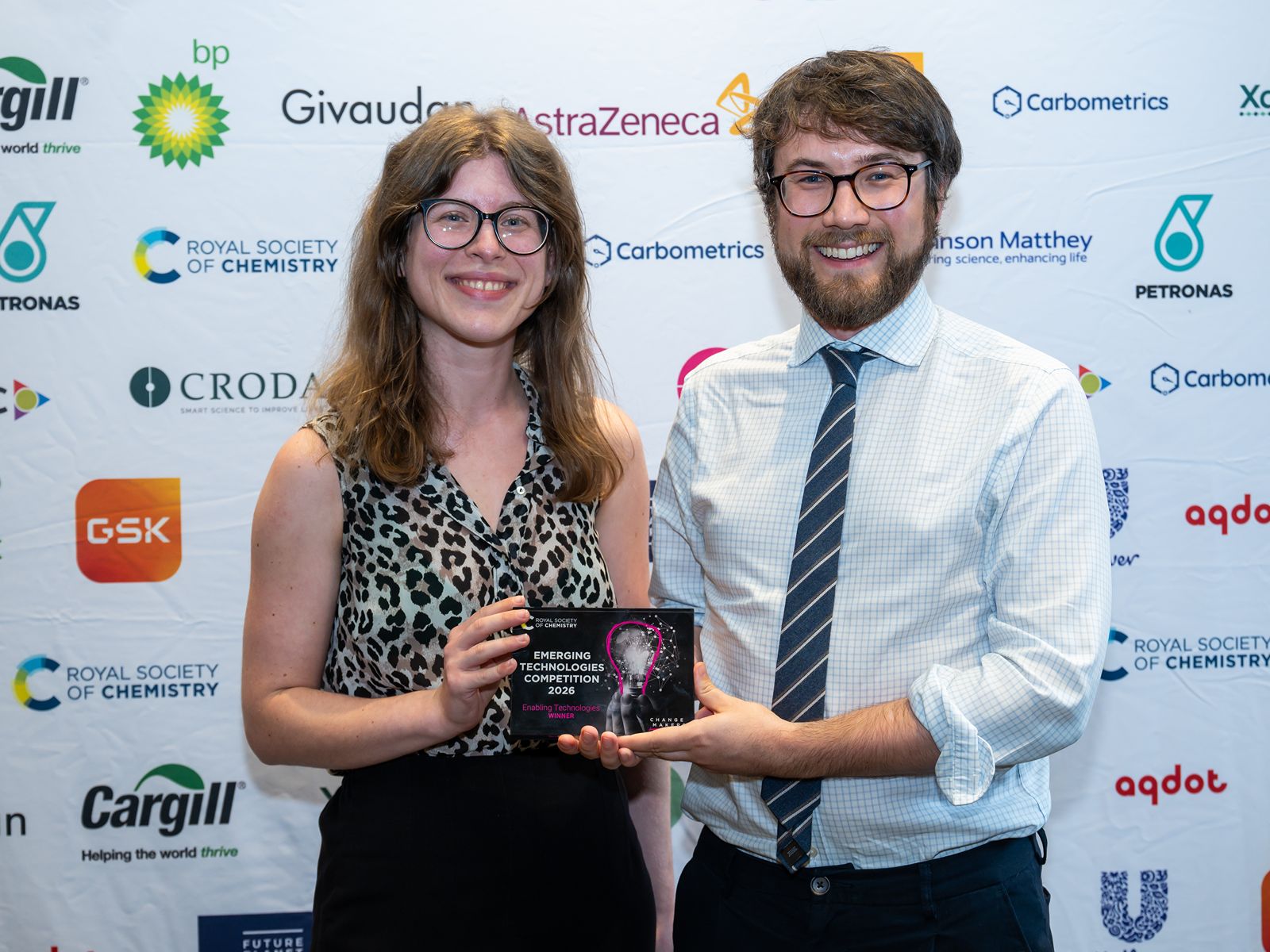 Claire Morley, lead biologist, and Jack Rowbotham, inventor and founder of Deuterose, smile and hold a plaque