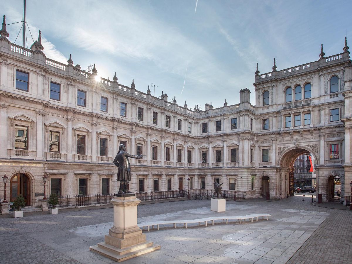 Historic white stone building with arch, Burlington House from inside the courtyard
