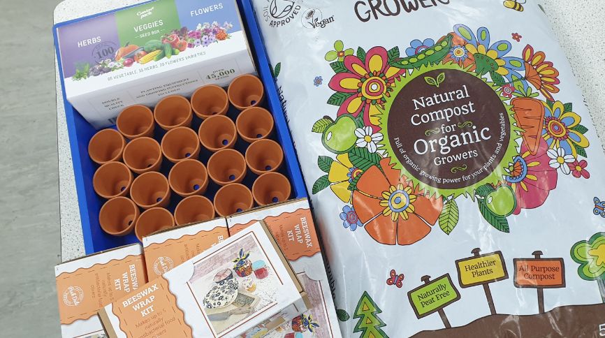 A box of seeds and a rows of empty plant pots which will be used to grow vegetables and herbs