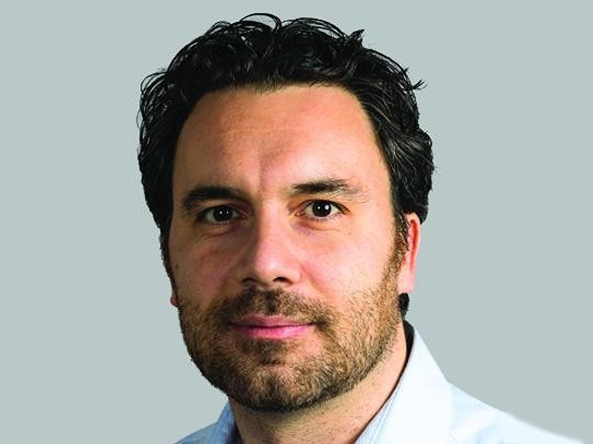 Marco Di Antonio smiling to camera with beard, moustach and wearing blue collared shirt