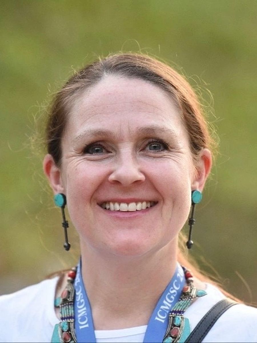 Sally Howells-Wyllie smiling to camera wearing long green earrings