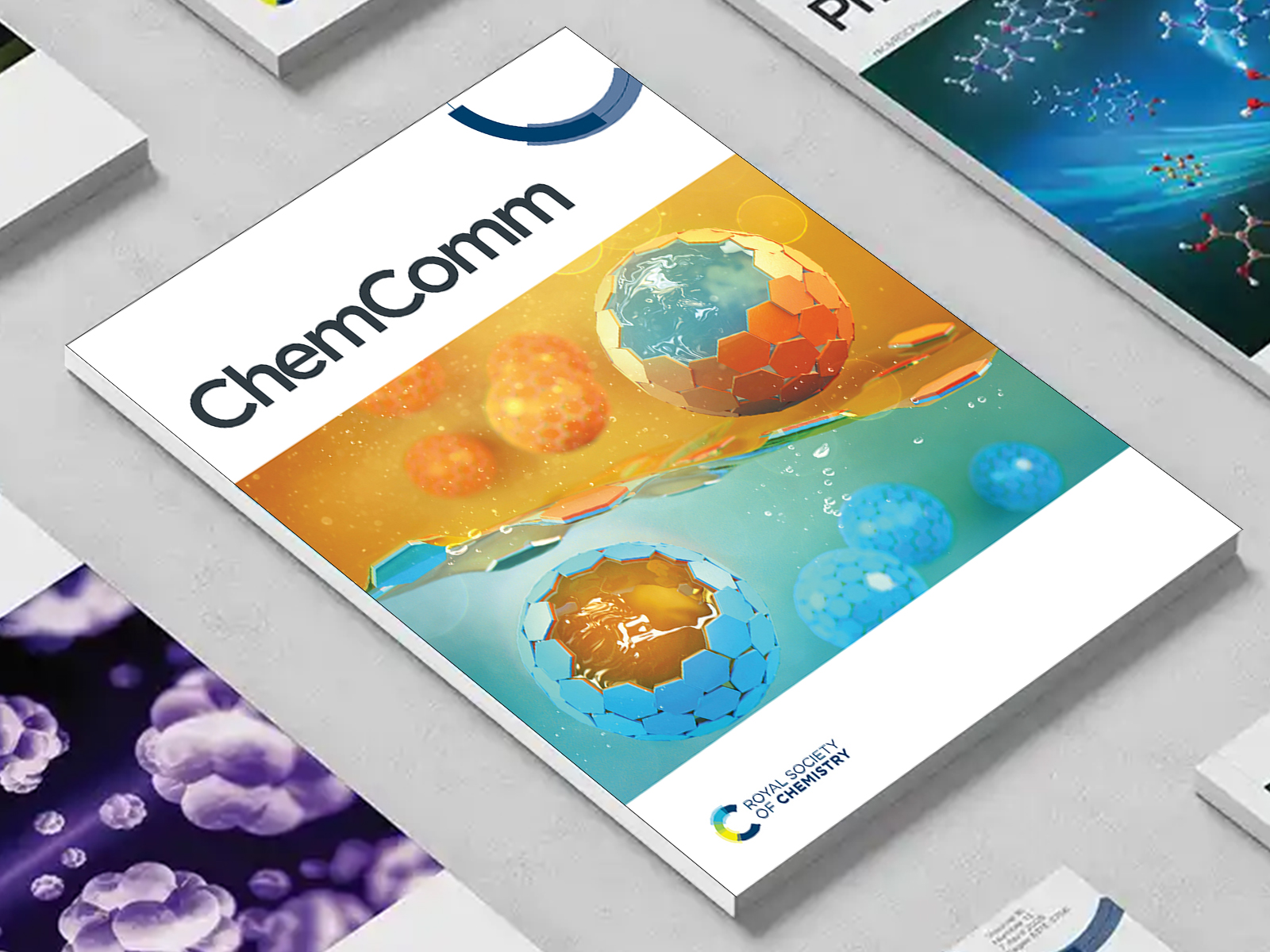 the ChemComm journal among a group of other journals on a desk