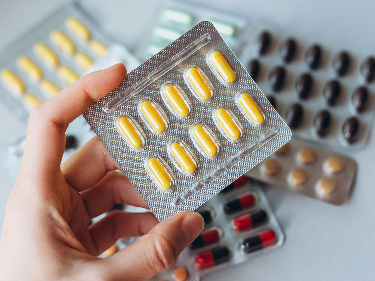 Female hand holds a package of yellow pills
