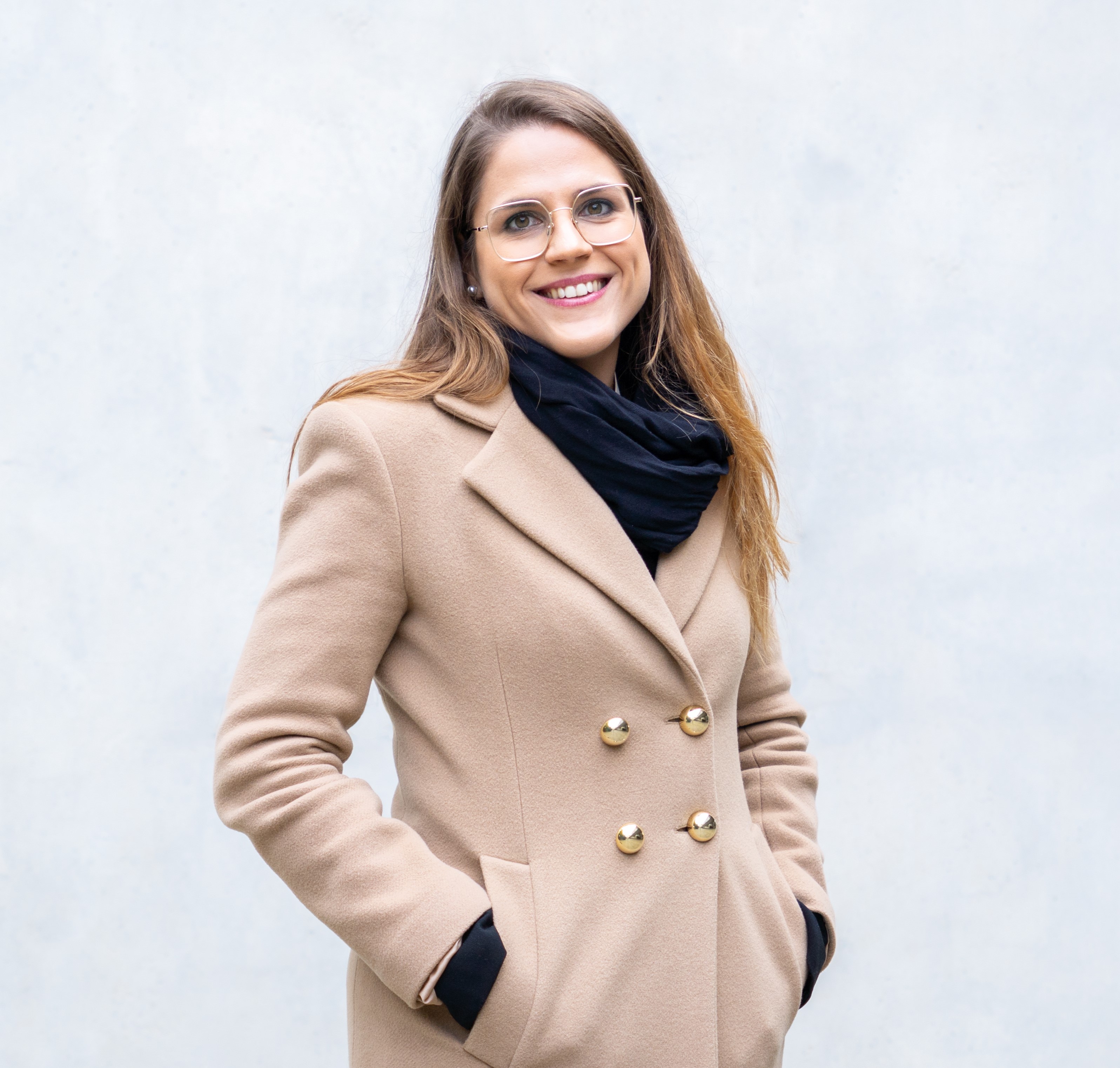 Carla Casadevall smiling at the camera, wearing a beige coloured coat