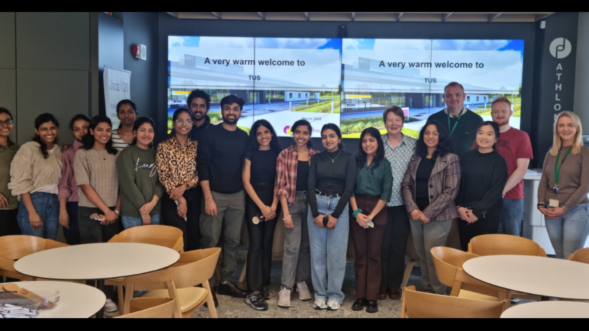 Virtual Labs Team students in front of large screen in a long line posing for camera