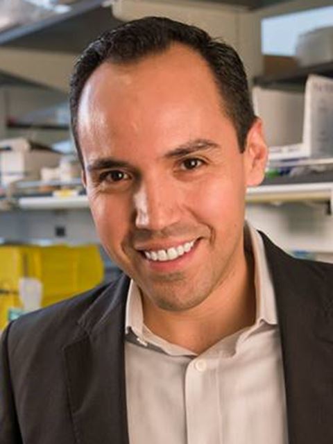 Luis smiling to camera in suit jacket and shirt