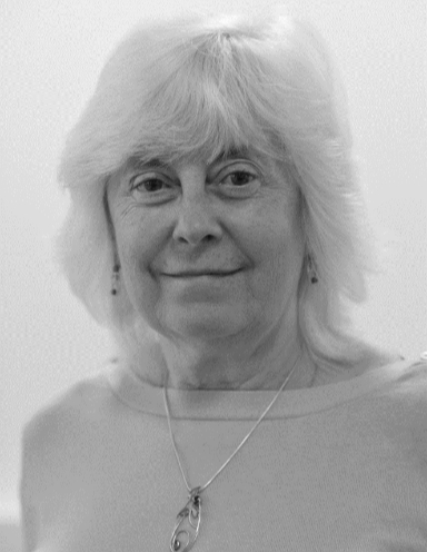 Black and white portrait of Professor Chris Willis, smiling, wearing a delicate pendant necklace.