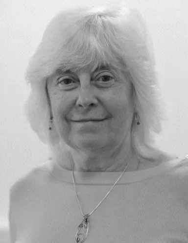 Professor Chris Willis Black and white portrait of Professor Chris Willis, smiling, wearing a delicate pendant necklace.