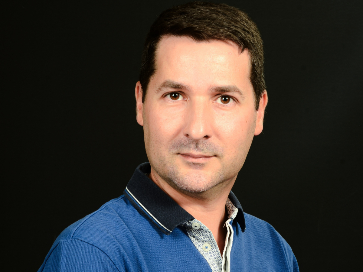 Eduardo Bolea-Fernández looking directly into the camera, wearing a blue polo shirt against black background.