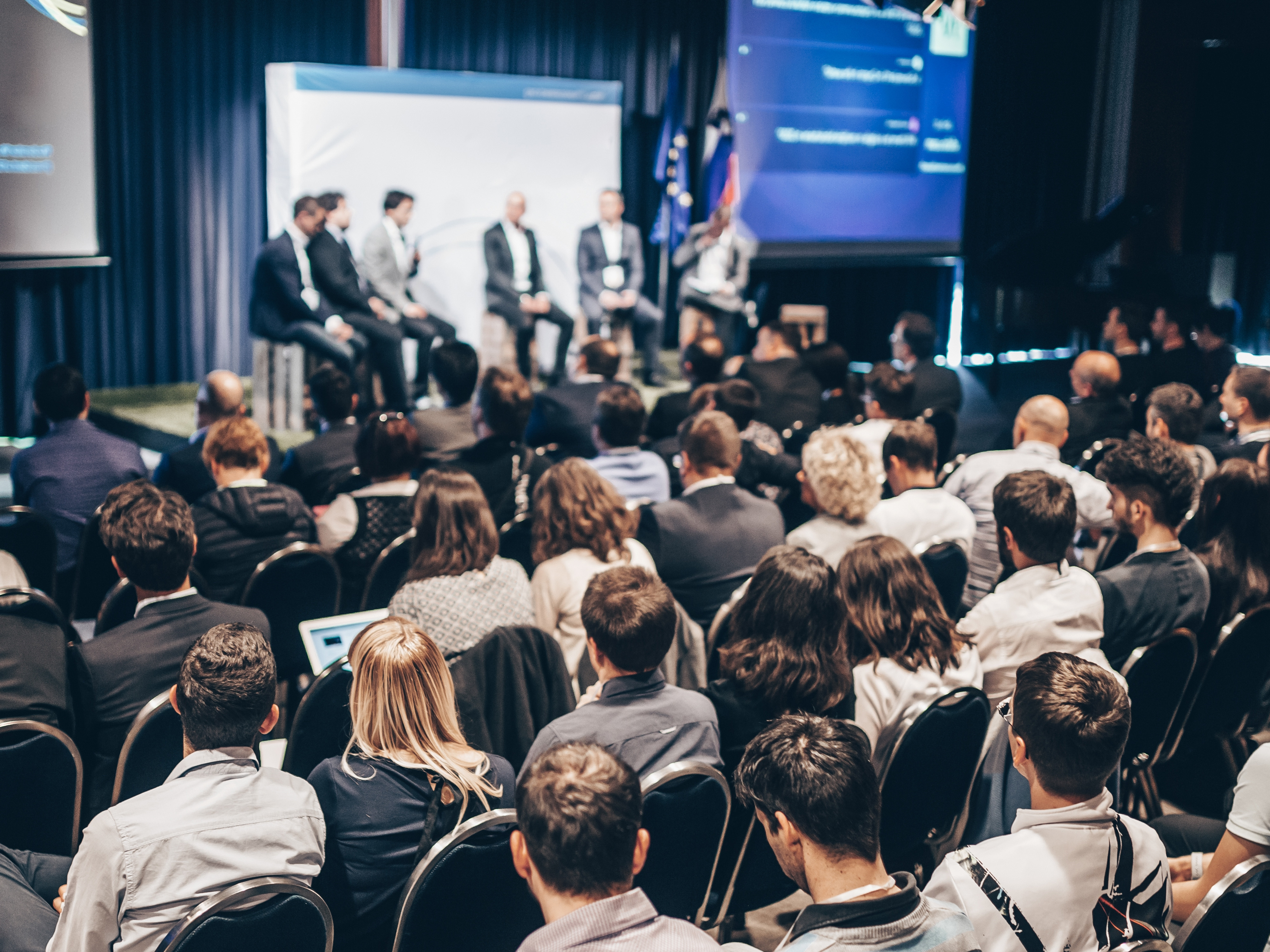 Seated attendees listening to speakers on a stage
