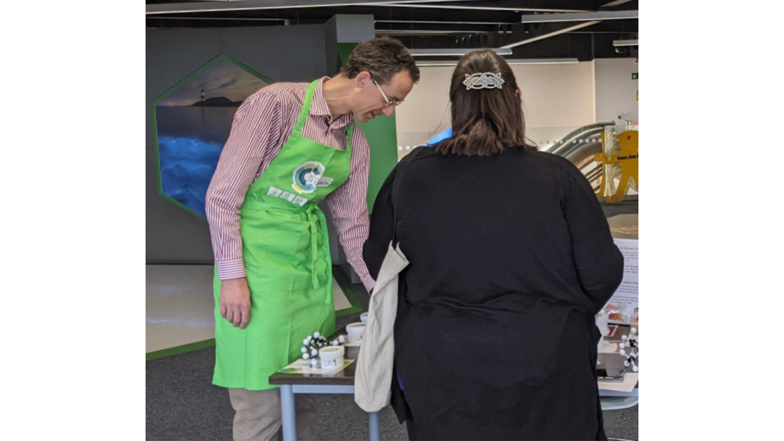 Dr James Redman with green apron with RSC logo on it, demonstrating with equipment