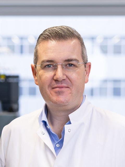 Ryan Gilmour headshot, in glasses and white lab coat