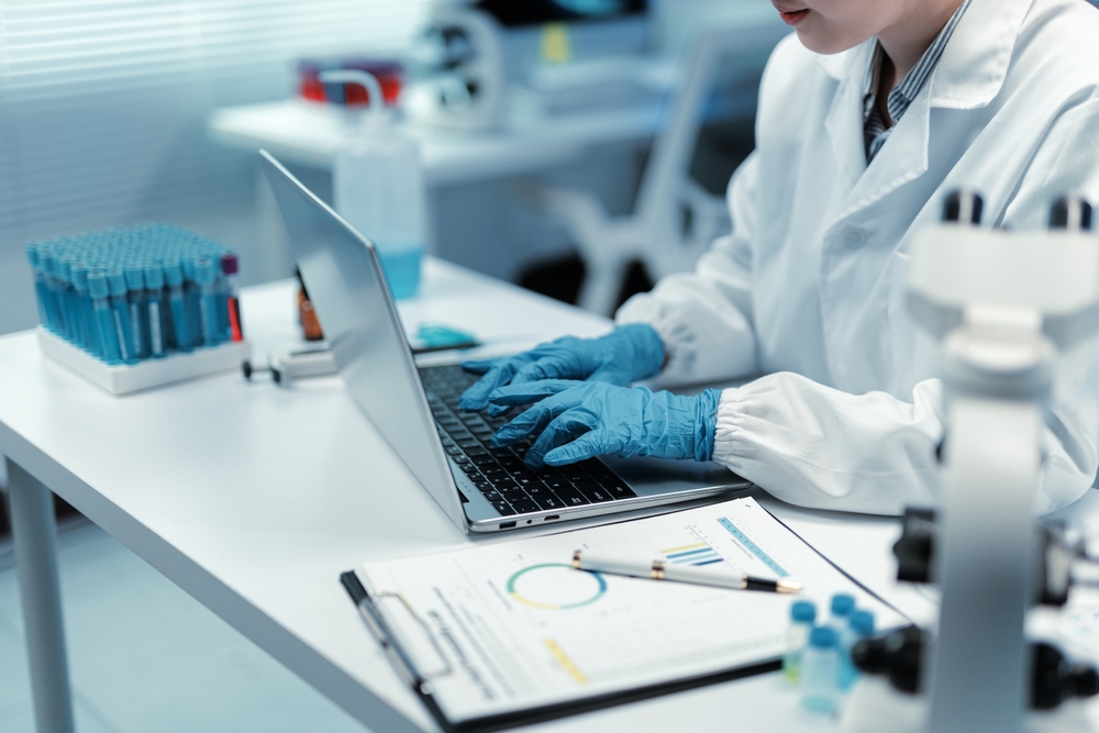 Close up of scientist hands typing on laptop keyboard in laboratory