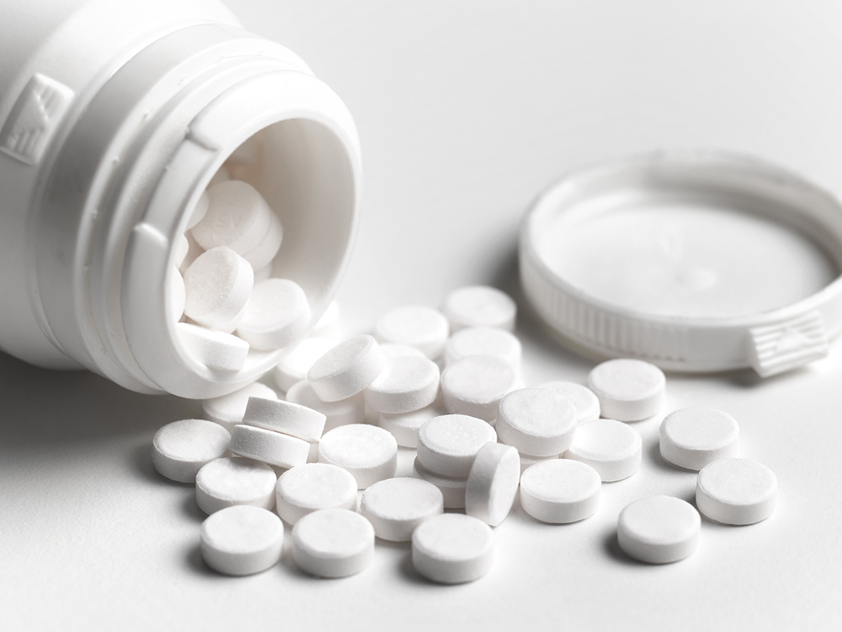 Container of white tablets open and small tablets spilling out