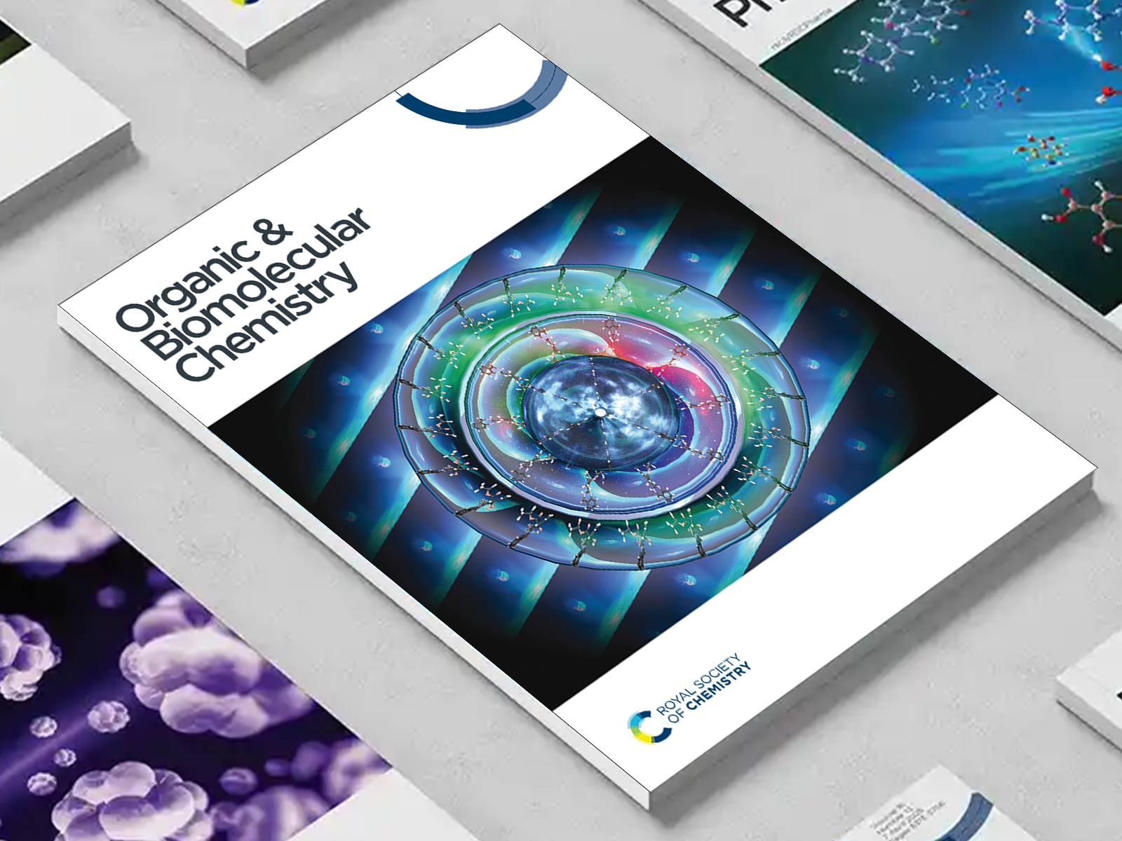 the Organic & Biomolecular Chemistry journal among a group of other journals on a desk