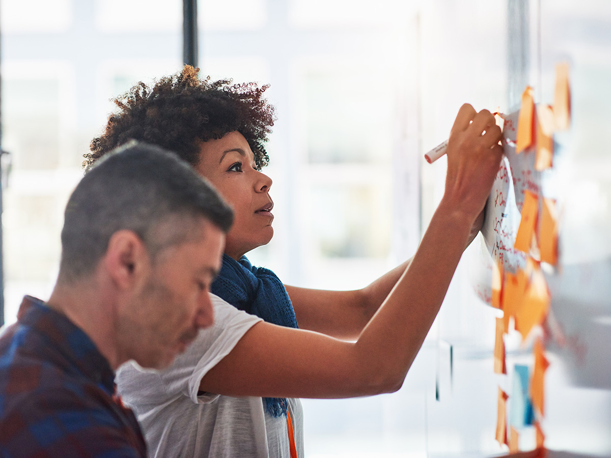 Two people interacting with post-in notes on a whiteboard