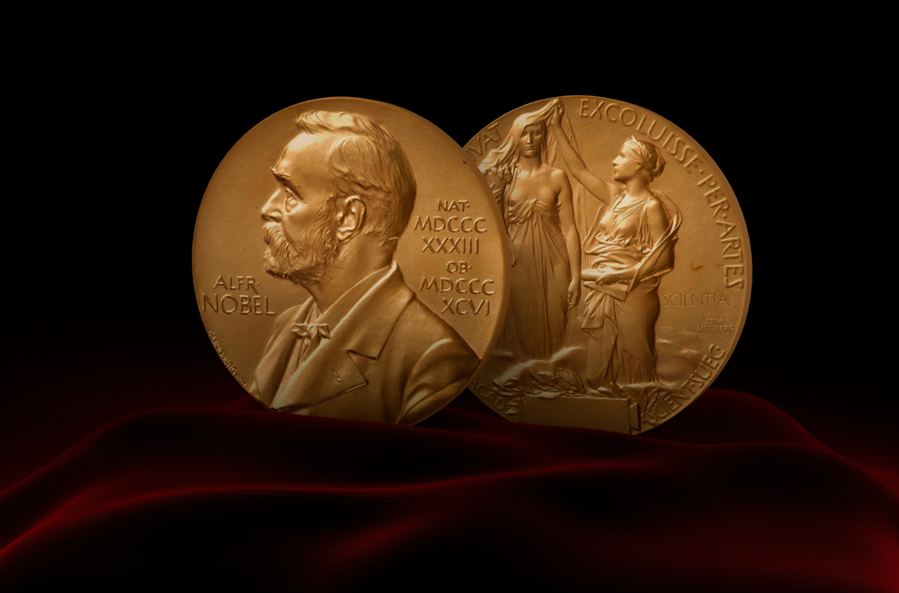 A Nobel Prize Medal standing on a platform set against a red and black background.