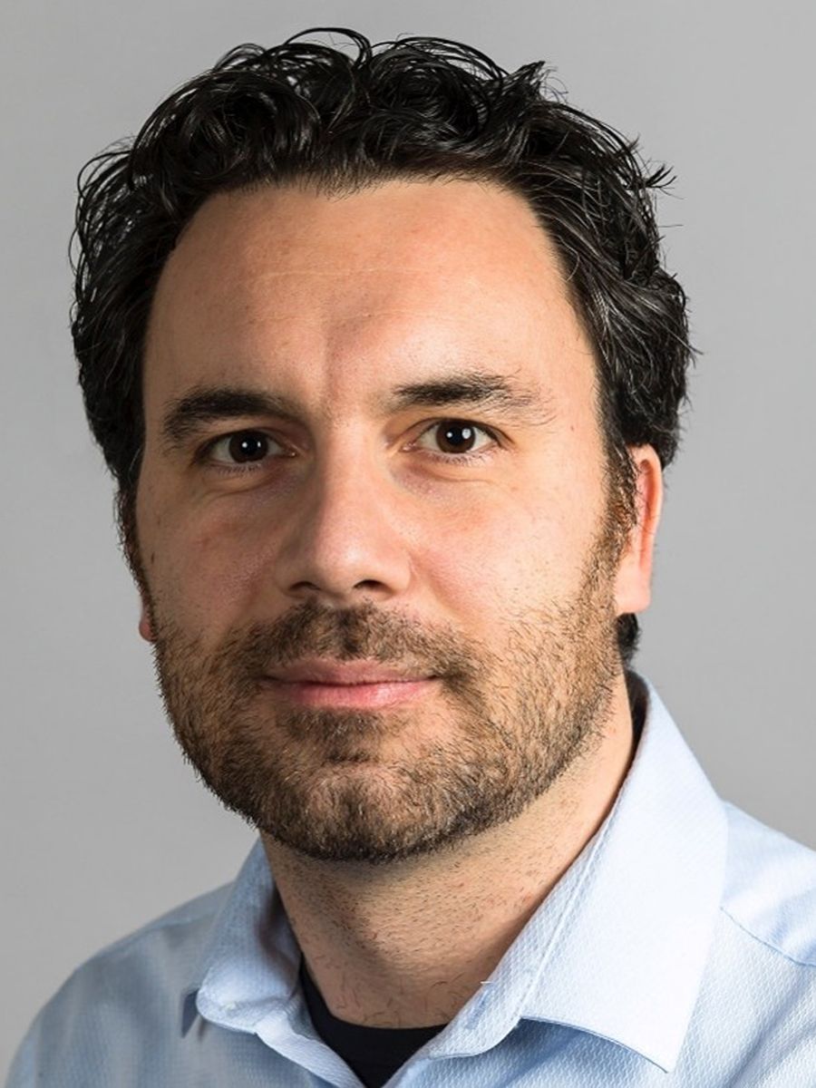 Marco Di Antonio smiling to camera with beard, moustach and wearing blue collared shirt
