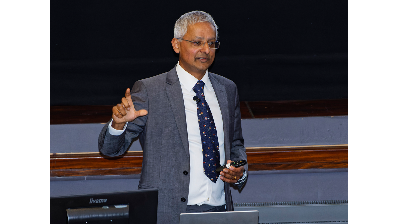 Professor Sir Shankar Balasubramanian in a suit and tie delivering a seminar