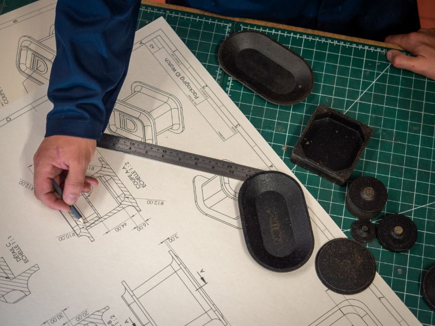 An arm holds a pencil over some schematics as work goes on to develop Notpla Rigid