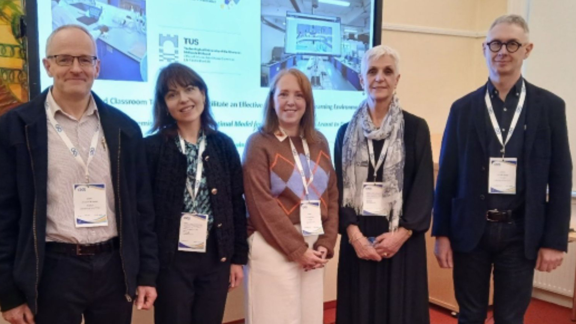 Some of Virtual Labs Team posing to camera in front of large screen