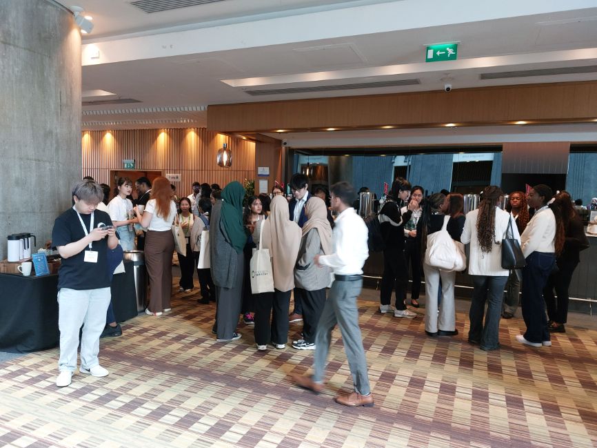 Groups of people stand around talking in a hotel lobby area