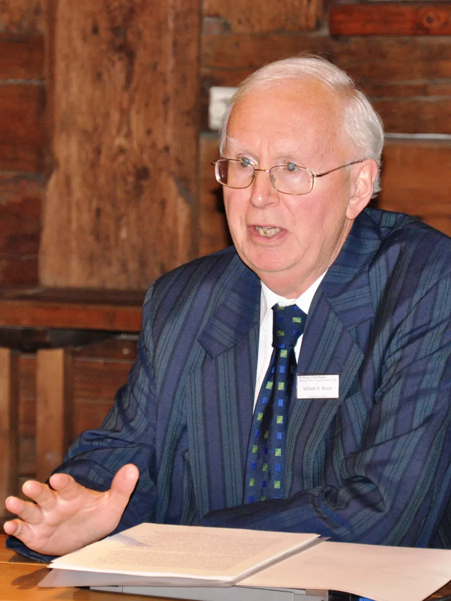 William Hodson Brock Professor William Hodson (“Bill”) Brock in suit and tie, glasses, talking at a panel