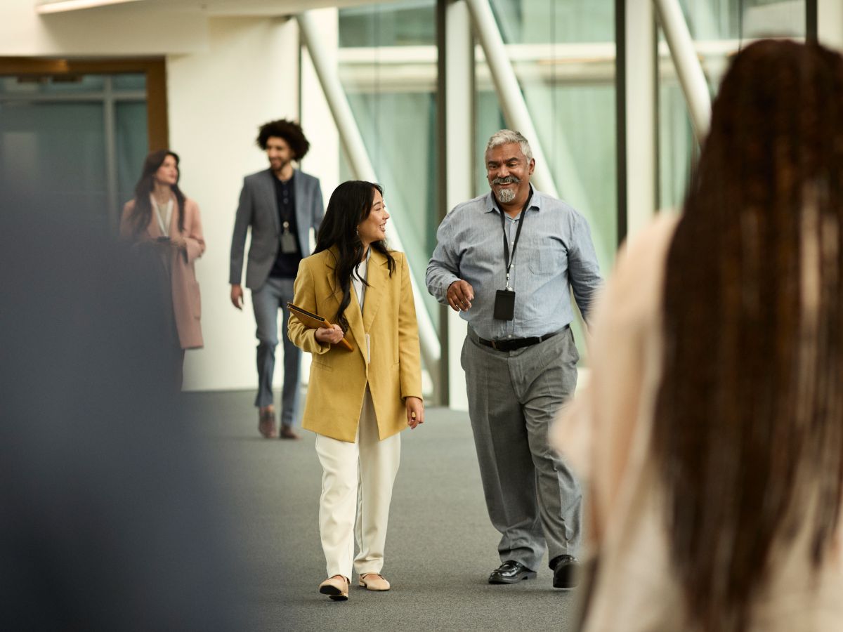 People of mixed gender and race walking along corridor of office