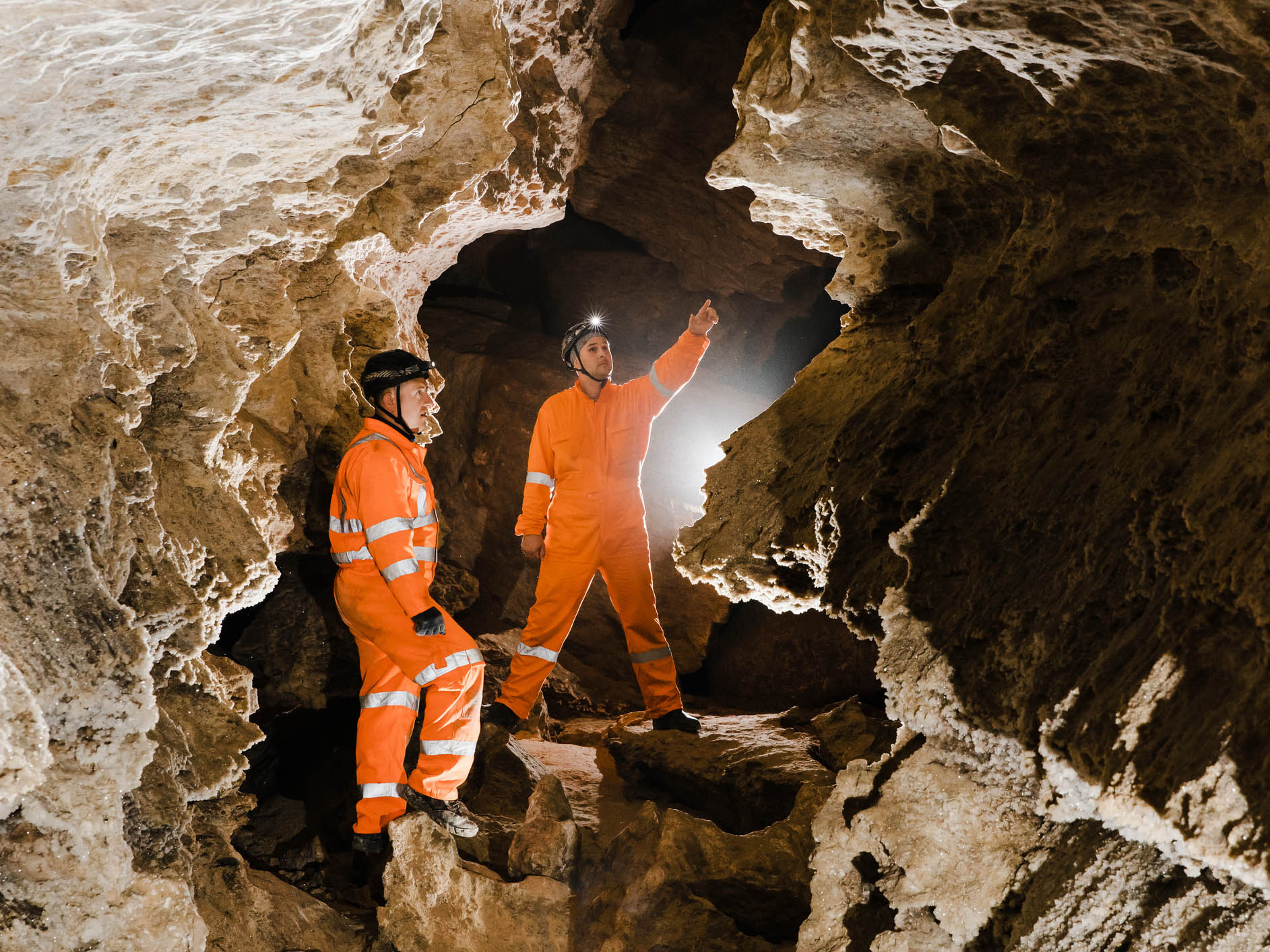 Two men in high visibility overalls explore a cave system