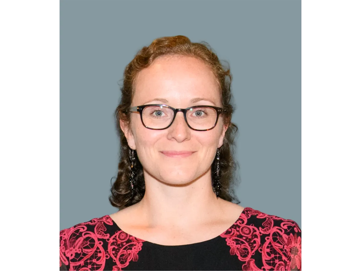 Professor Kim Jelfs wearing glasses and a red and black shirt, smiling for the camera