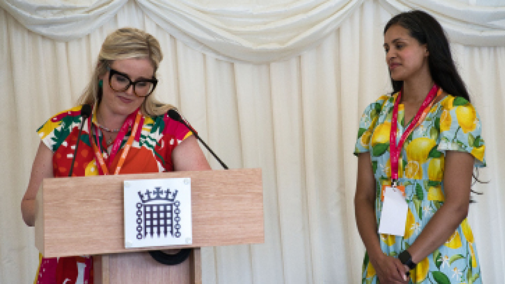 Jorden and Laura standing at podium in colourful dresses 