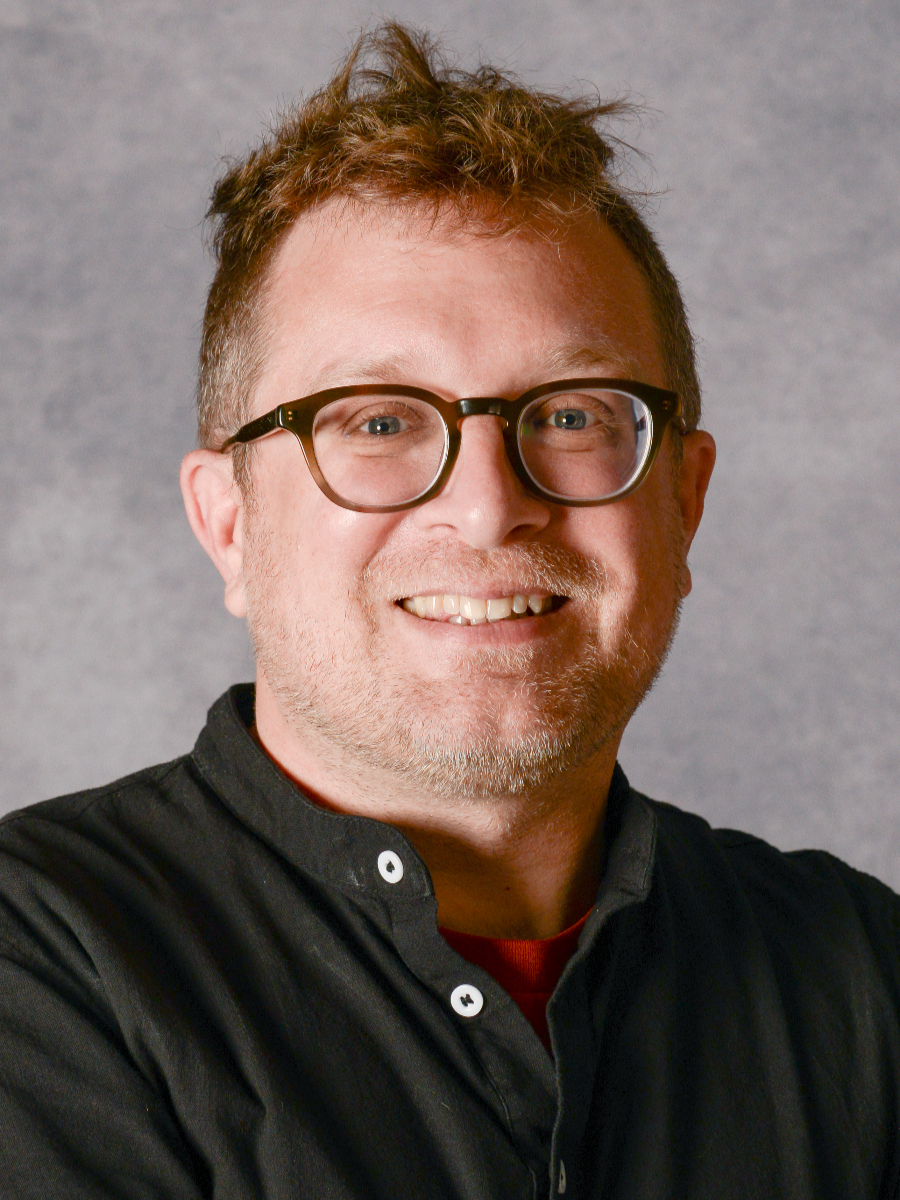 Matthew Lockett smiling to camera in glasses and grey shirt