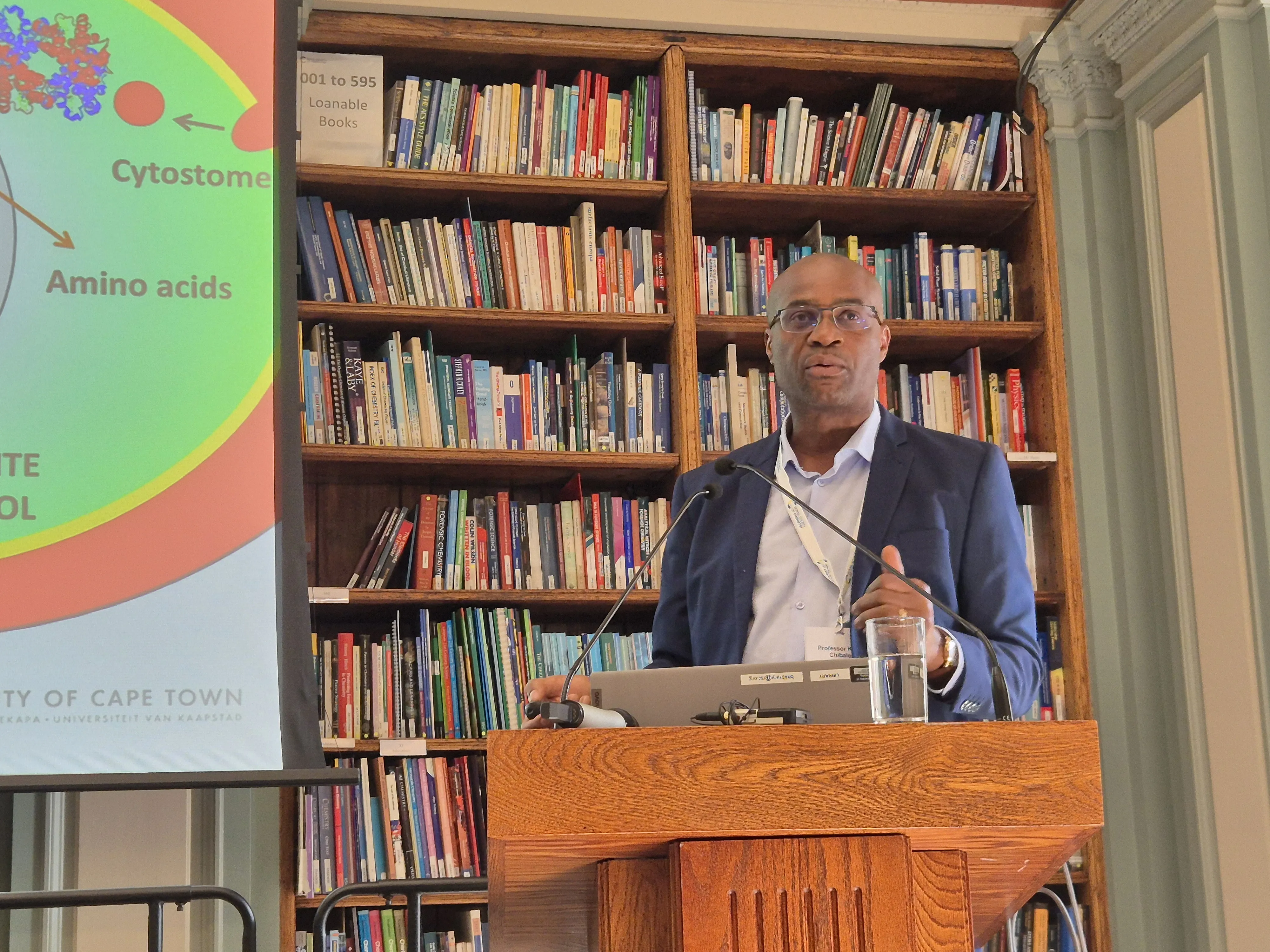 2026 Chemical Biology Symposium - Professor Kelly Chibale presents Professor Kelly Chibale stands at a lectern and faces a crowd (out of shot)