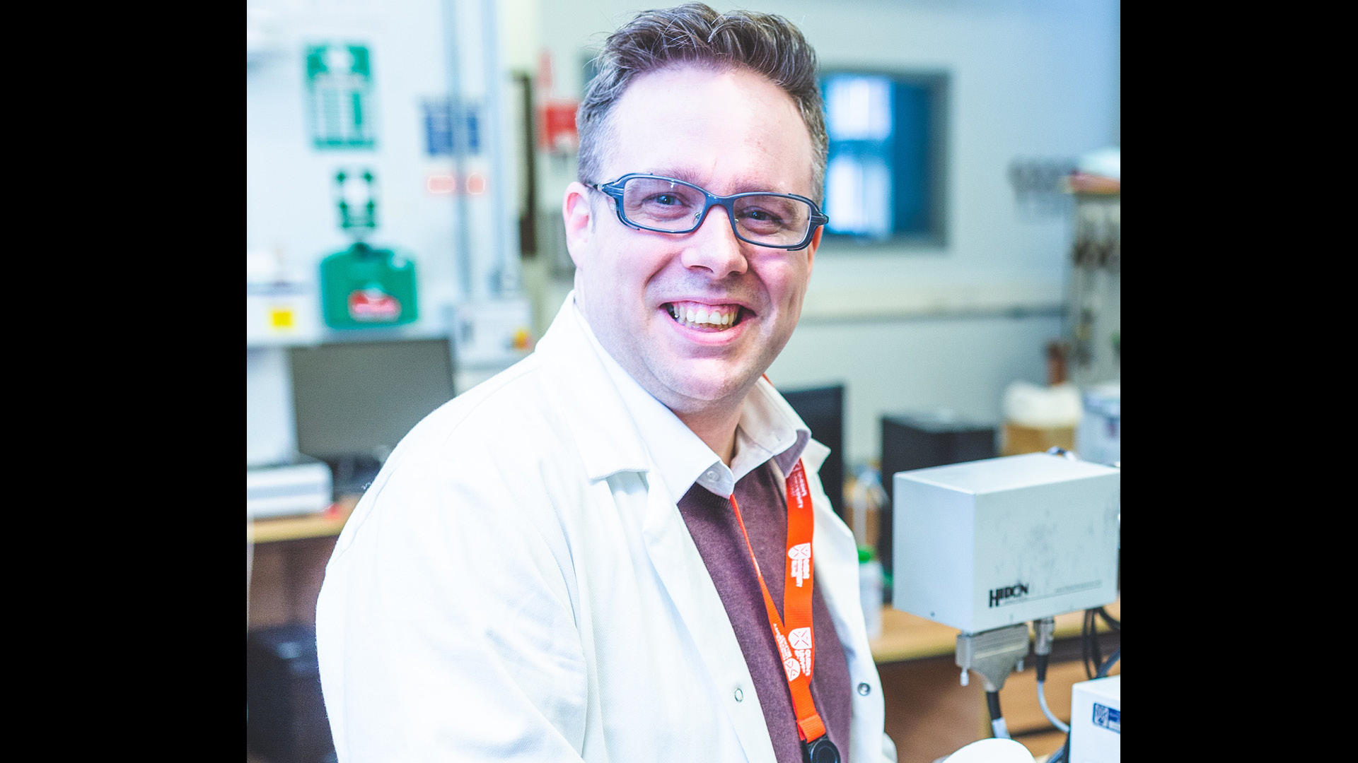 Kevin Morgan smiling to camera in lab coat and glasses