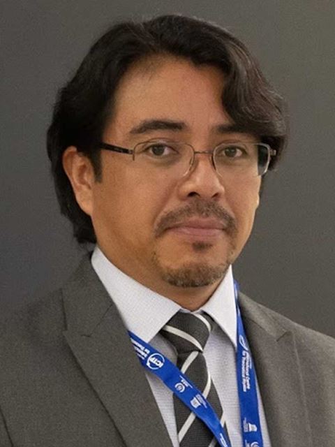 Gabriel Merino headshot in grey suit jakcet, white shirt and tie, and glasses