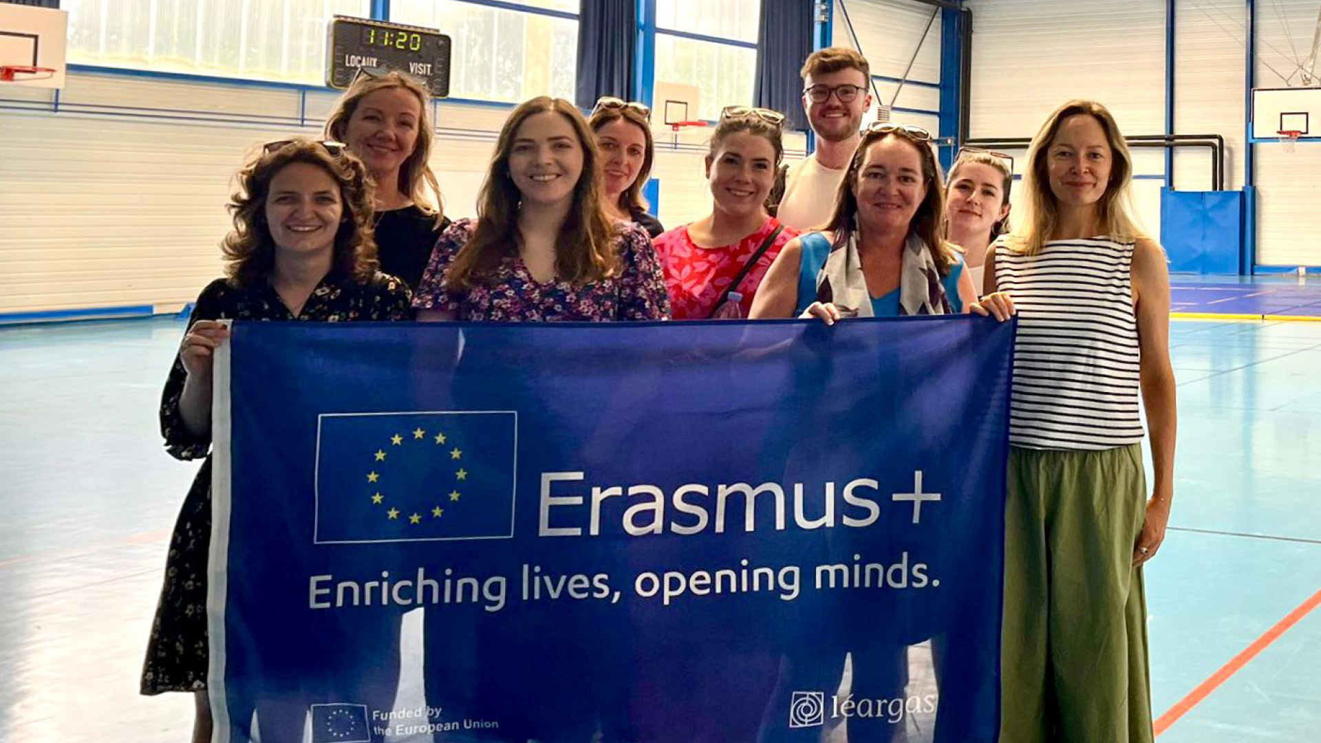 Conor Eivers with team holding banner with Erasmus+ logo which says Enriching lives, opening minds